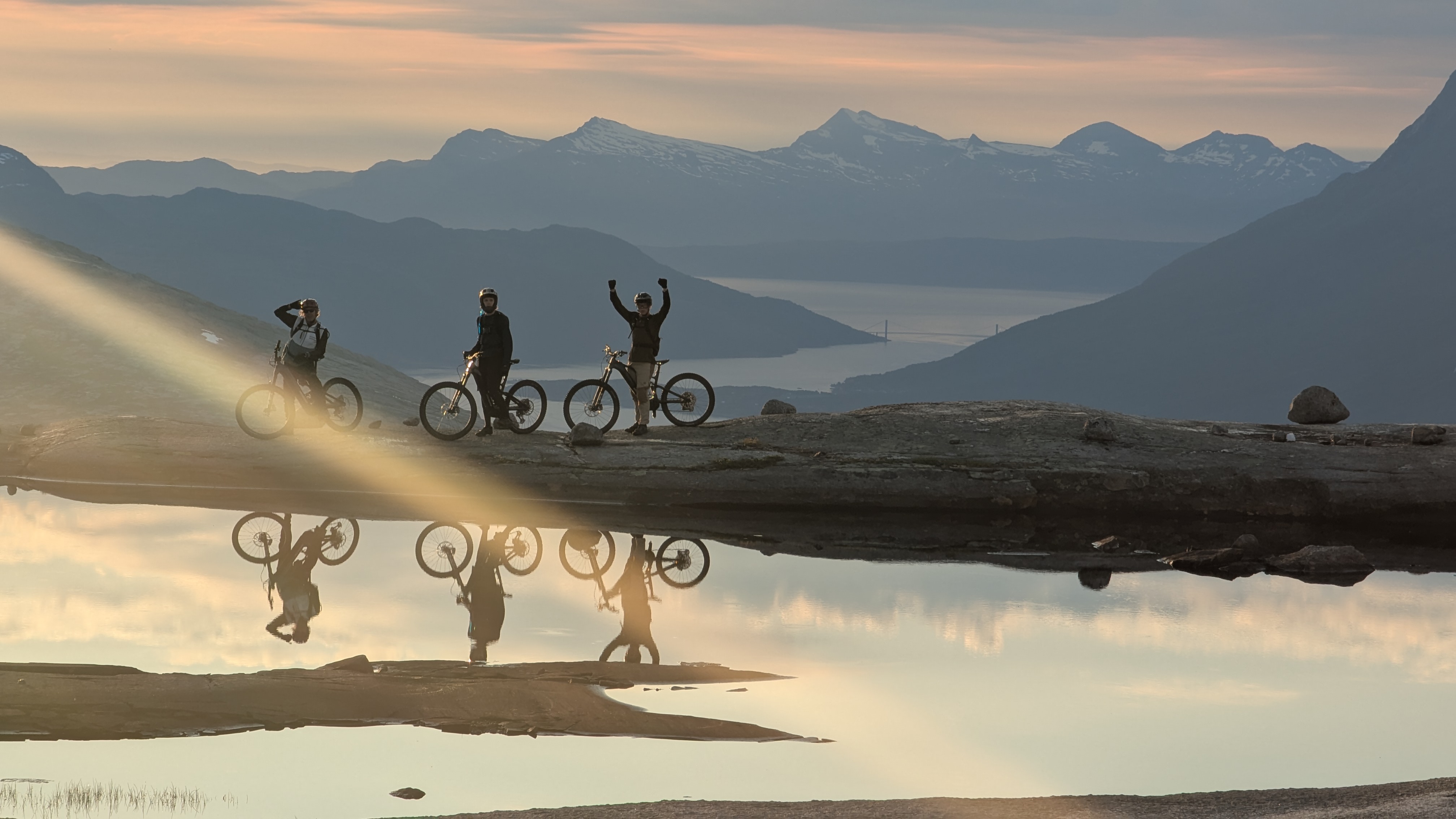 Three mountabikers in sunset at mountain