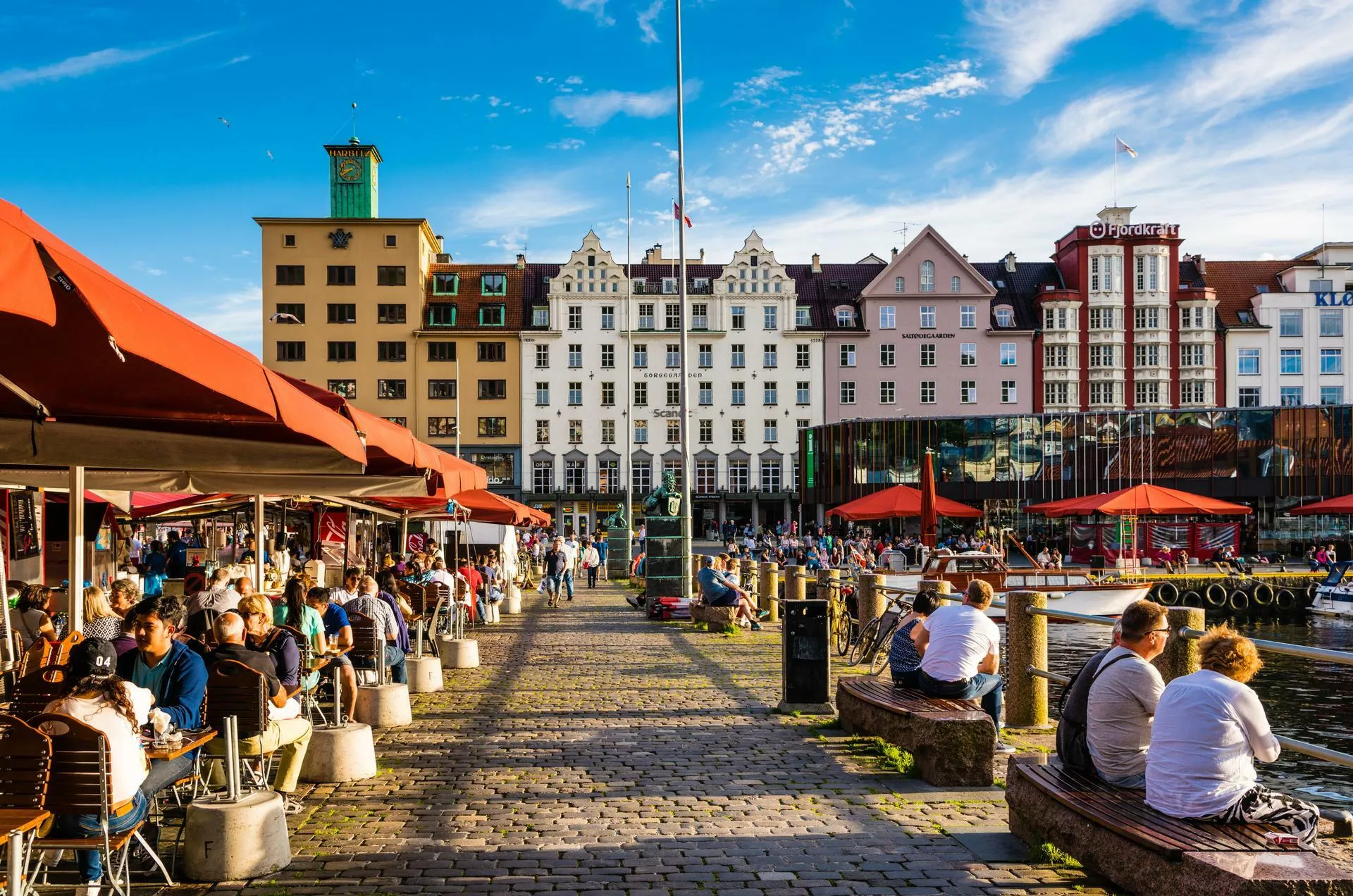 Coloful buildings with people sitting on benches and a blue sky.