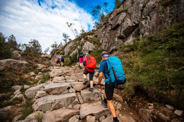 Hikers walking up a rocky mountain trail with backpacks.
