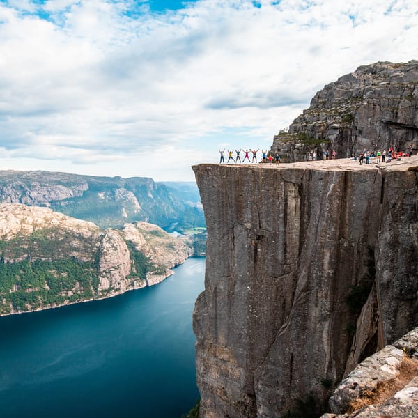 Happy hikers jumping at the Pulpit Rock with Lysefjorden in the background