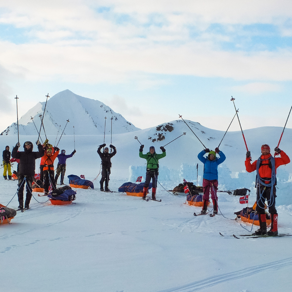 A bunch of skiers standing in front of the camera with their poles in the air
