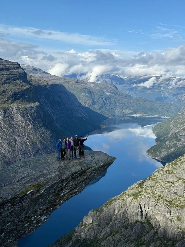 A group of people standing at Trolltunga with the blue fjord in the background.