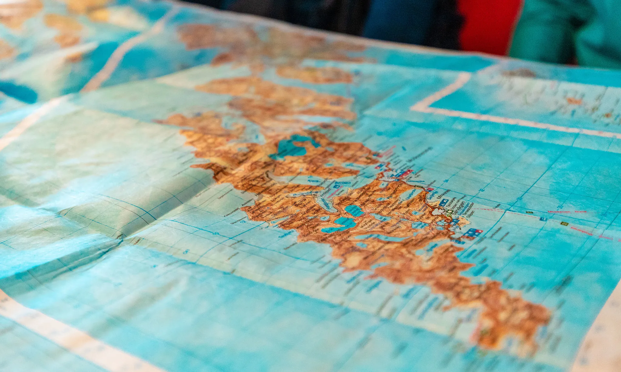 A large physical map showing a coastline with islands, spread out on a table.