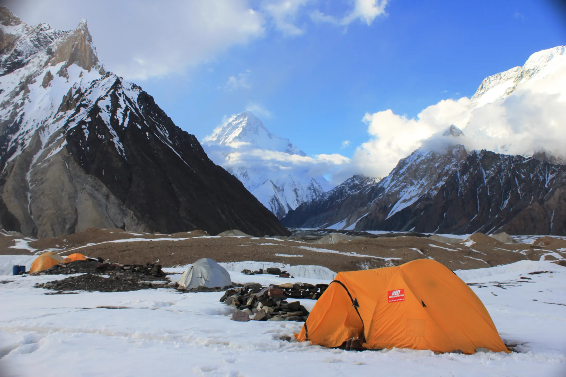 Tents in the mountains with snow on the ground.