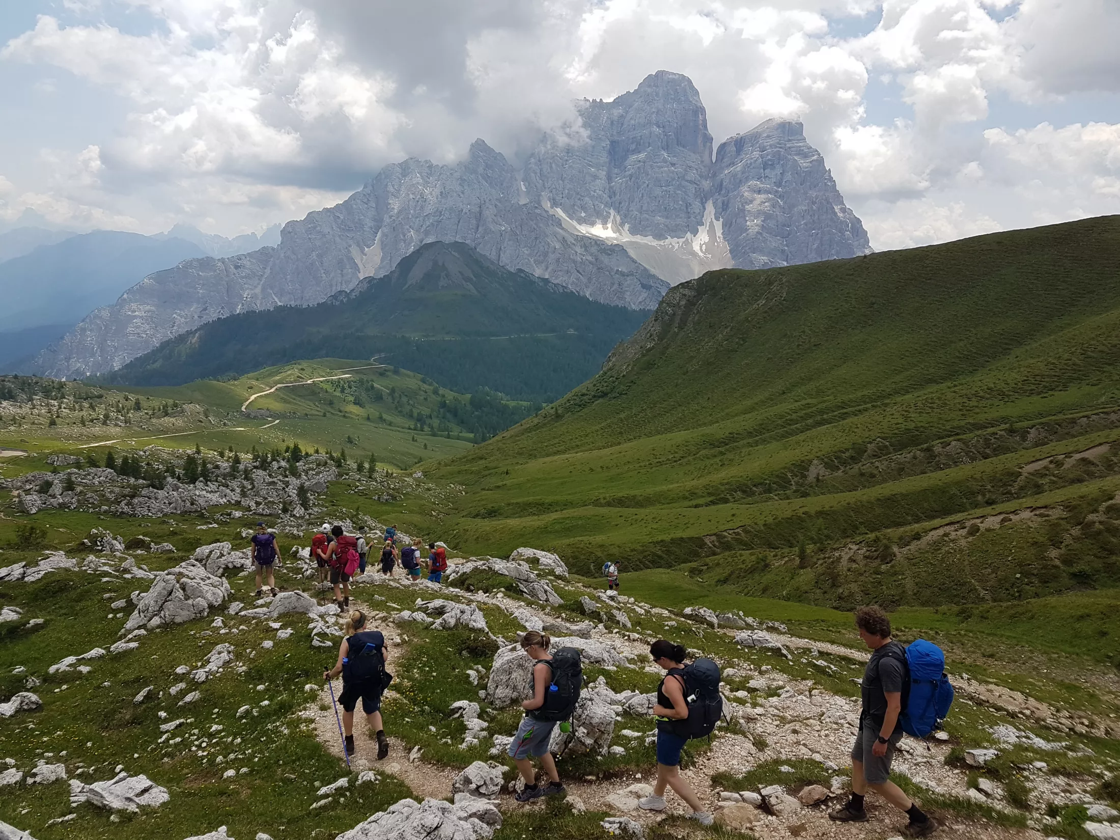People on trail in meadow in mountains