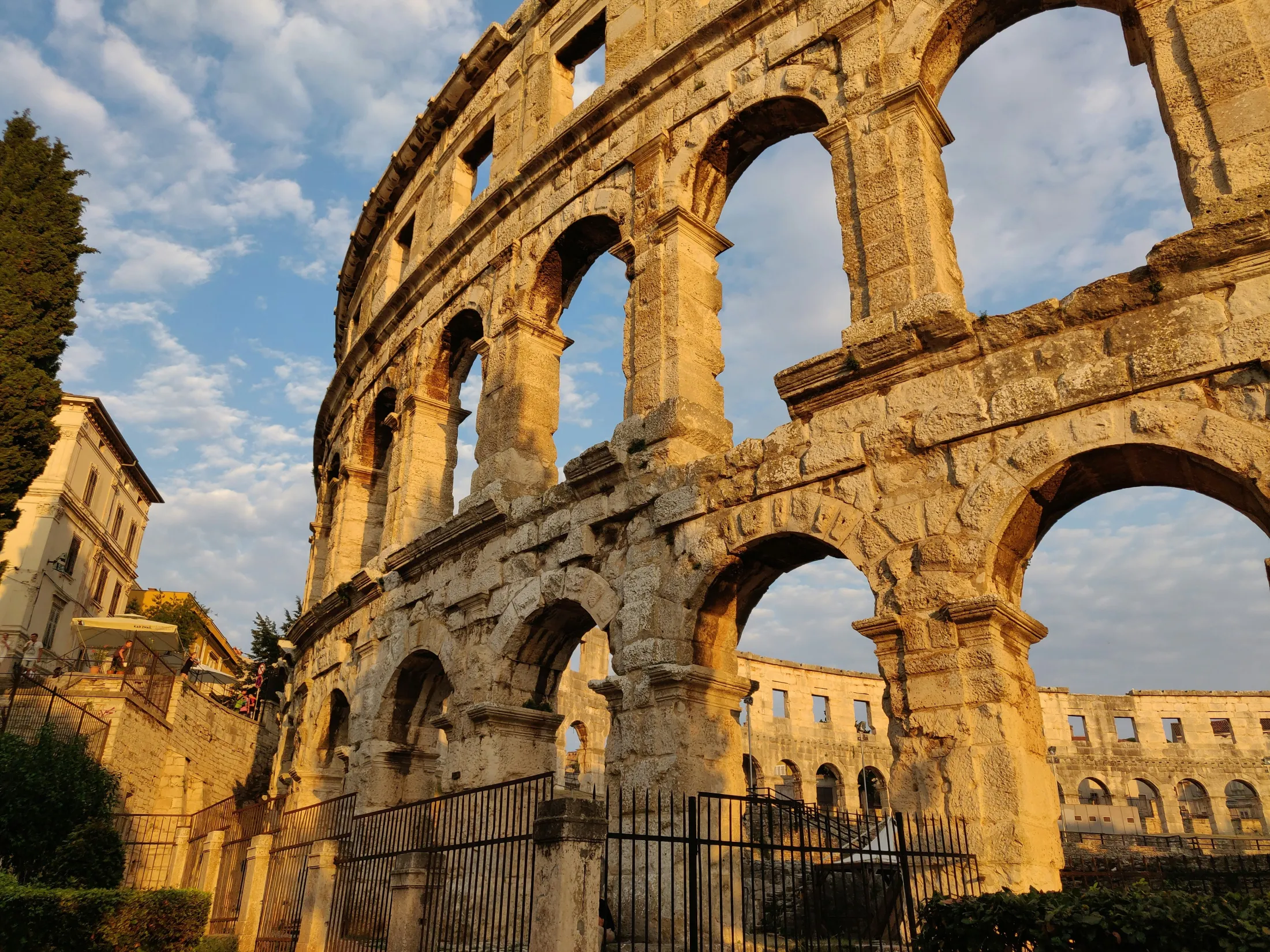 A close-up view of the stone arches of the Roman Amphitheatre in Pula against a cloudy sky.