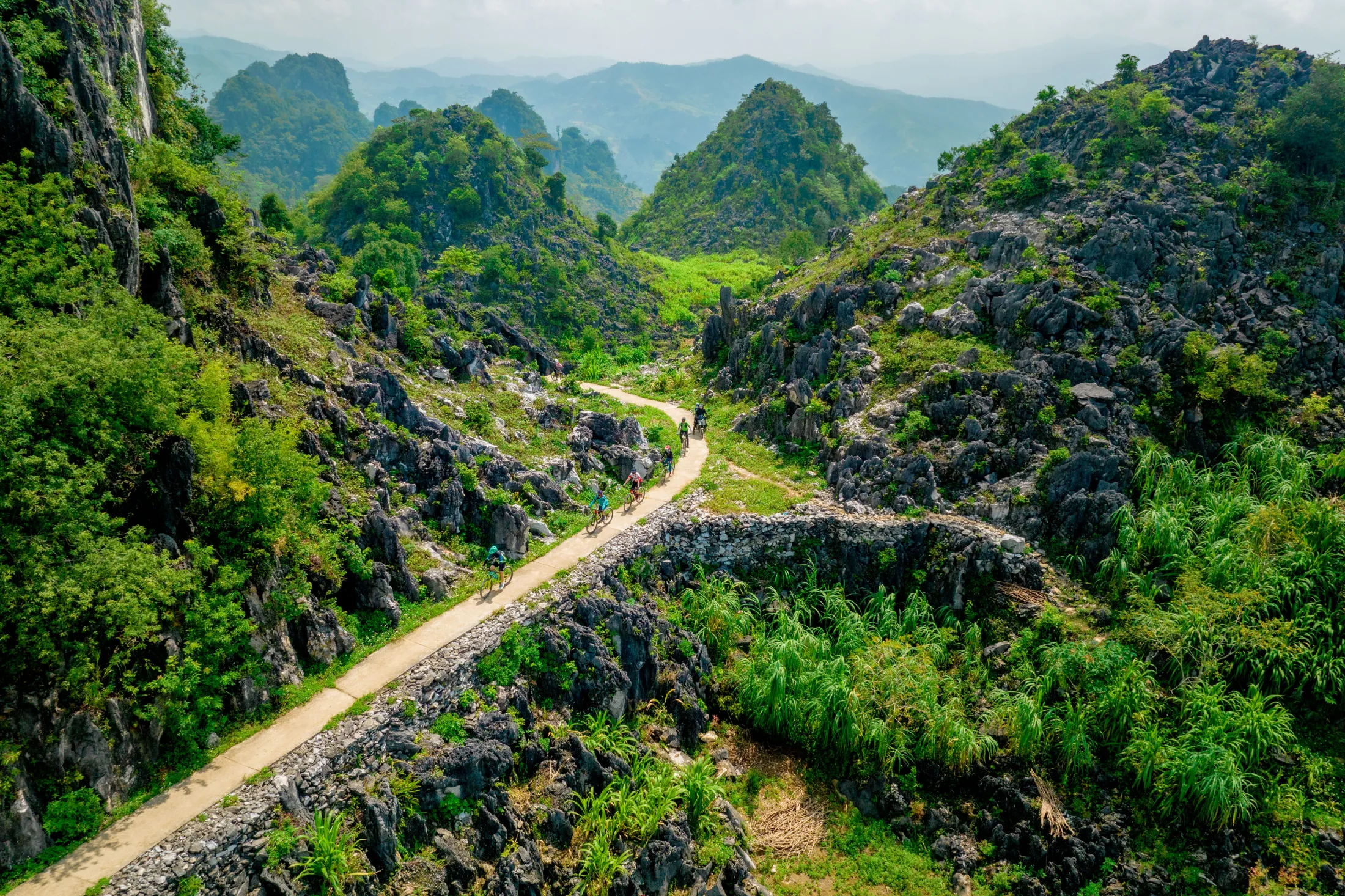 People biking on a path in mountains in Vietnam.