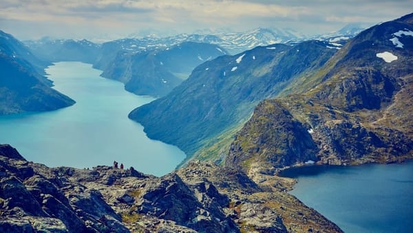 Scenic aerial view of a turquoise mountain lake nestled between steep, rugged peaks in Jotunheimen, Norway.
