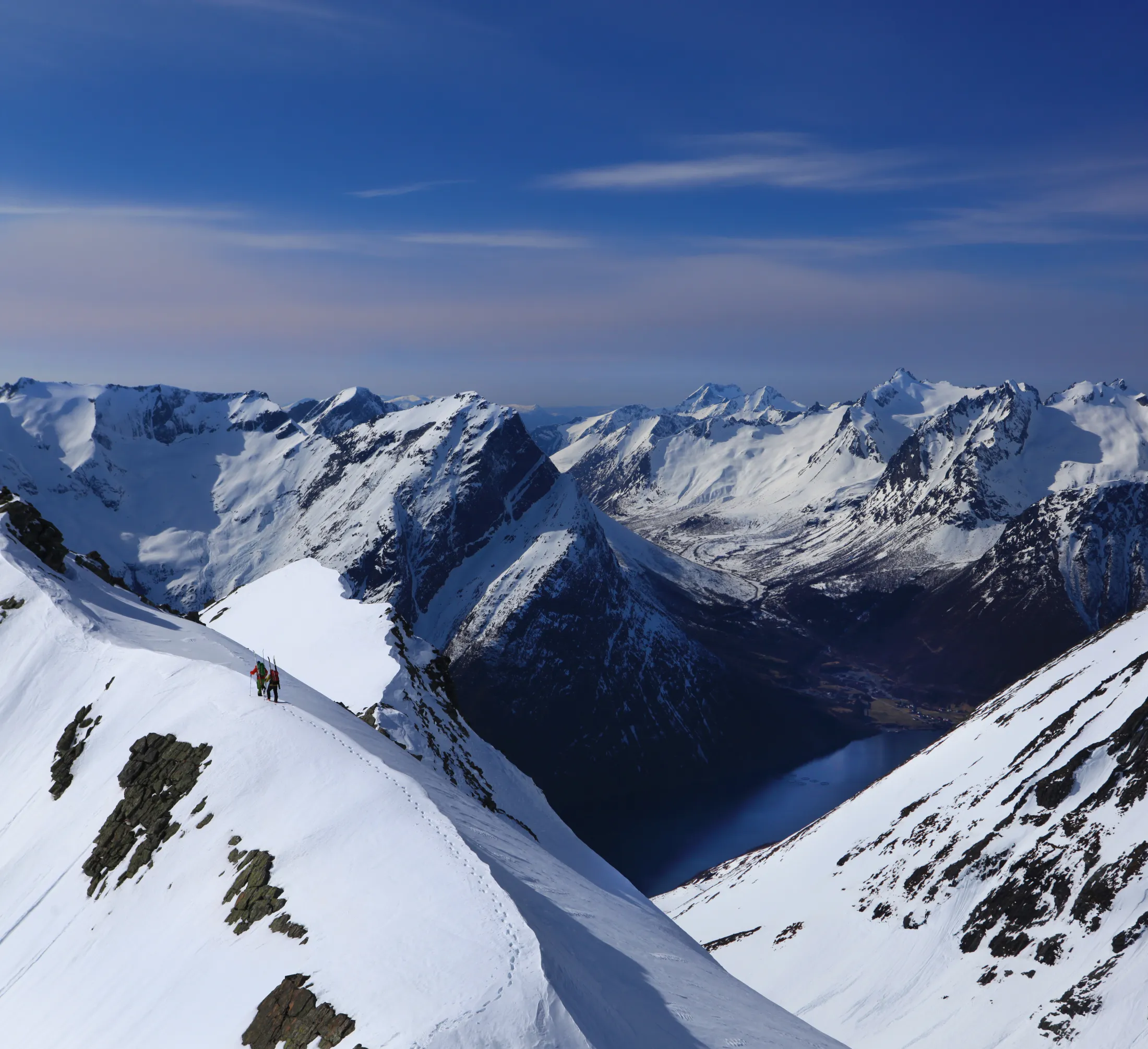A snowy mountain ridge stretching across a landscape under a blue sky.