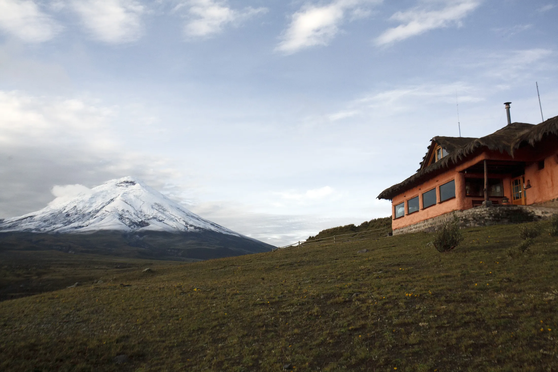A house on a hill with a snow-capped mountain in the background.