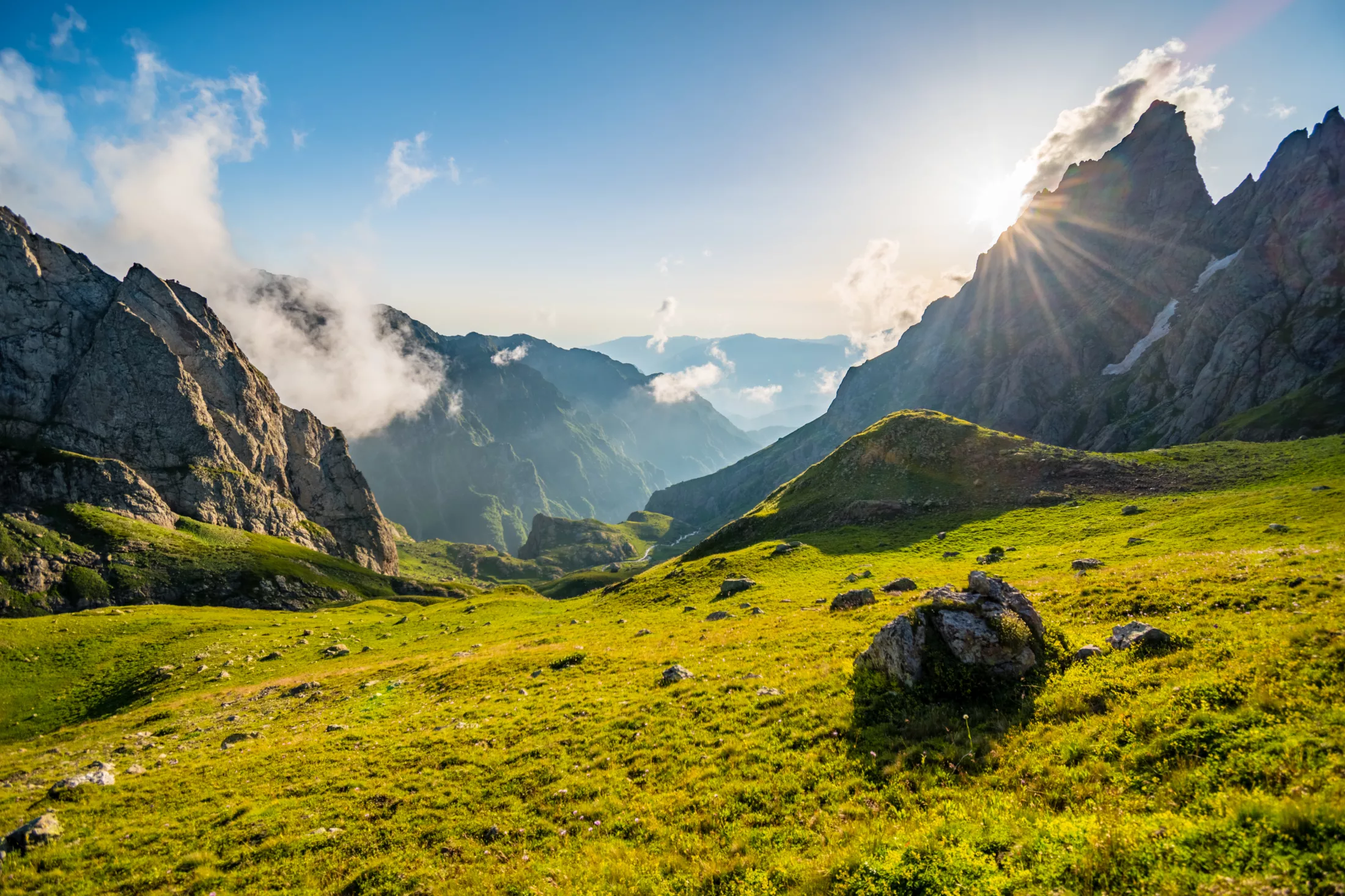 Blue skies, green meadows in a valley in mountains.
