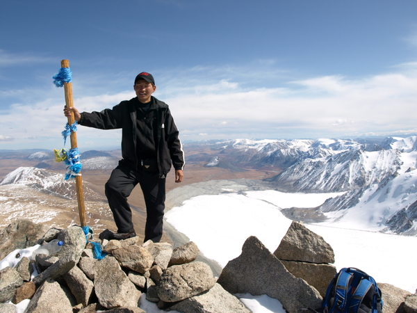 A man on top of a mountain with a glacier in the back