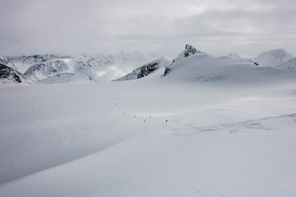 A snowy landscape with majestic mountains under a cloudy sky.