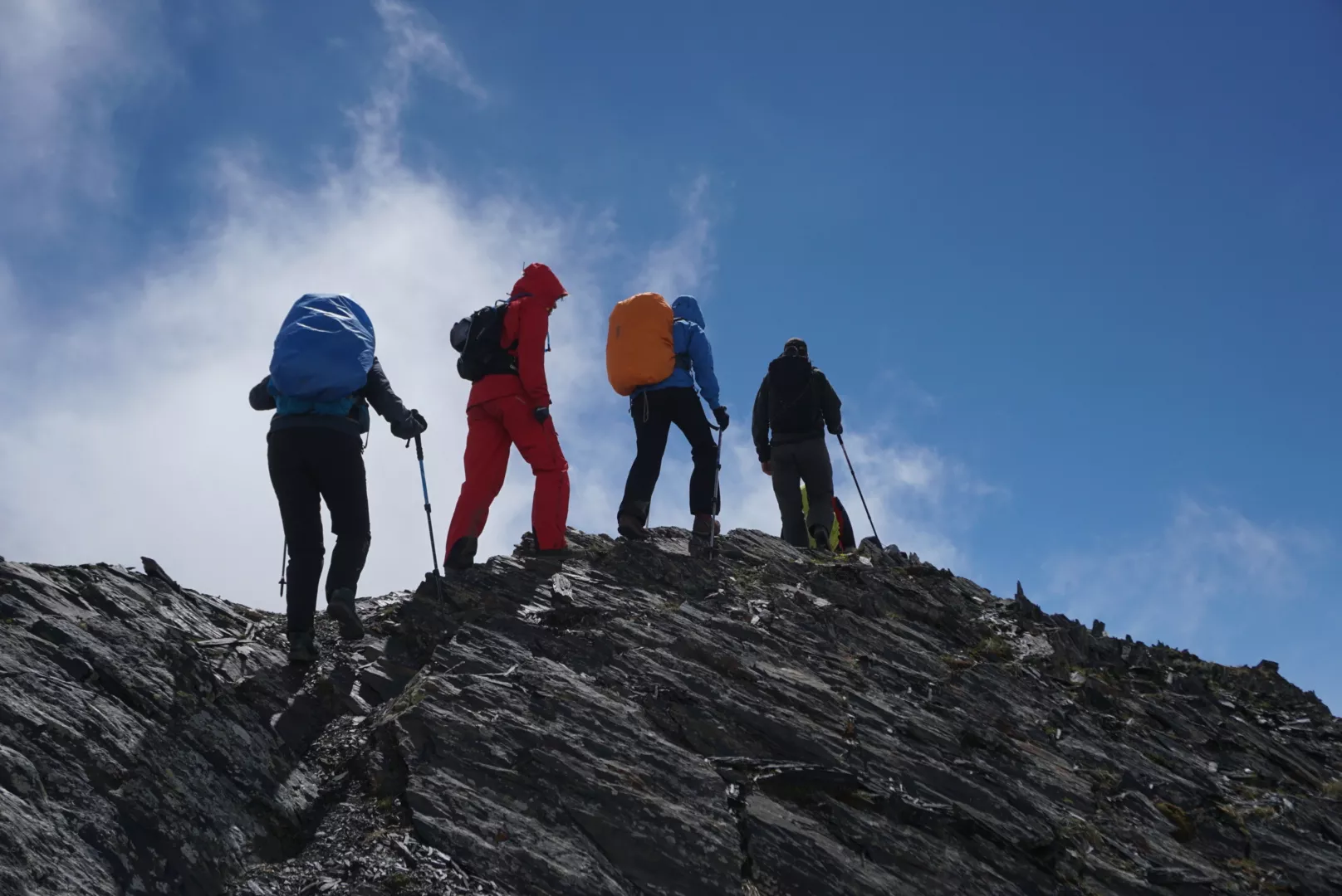 People crossing on a mountain ridge with blue skies