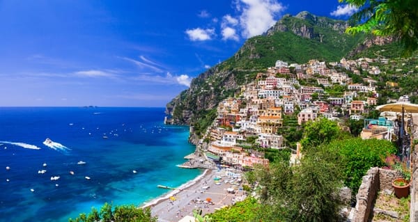 Scenic view of Positano along the Amalfi Coast with colorful houses, a pebble beach, and deep blue sea.