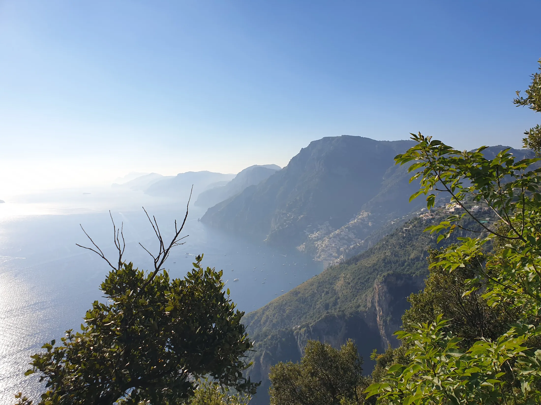 A scenic view of a steep coastline along a sparkling blue sea under a clear sky.