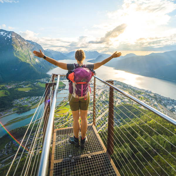Person standing at a viewpoint, looking down at Åndalsnes with the hands outstretched.
