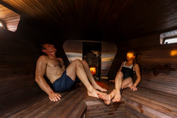 A man and a woman relaxing in a wooden sauna.