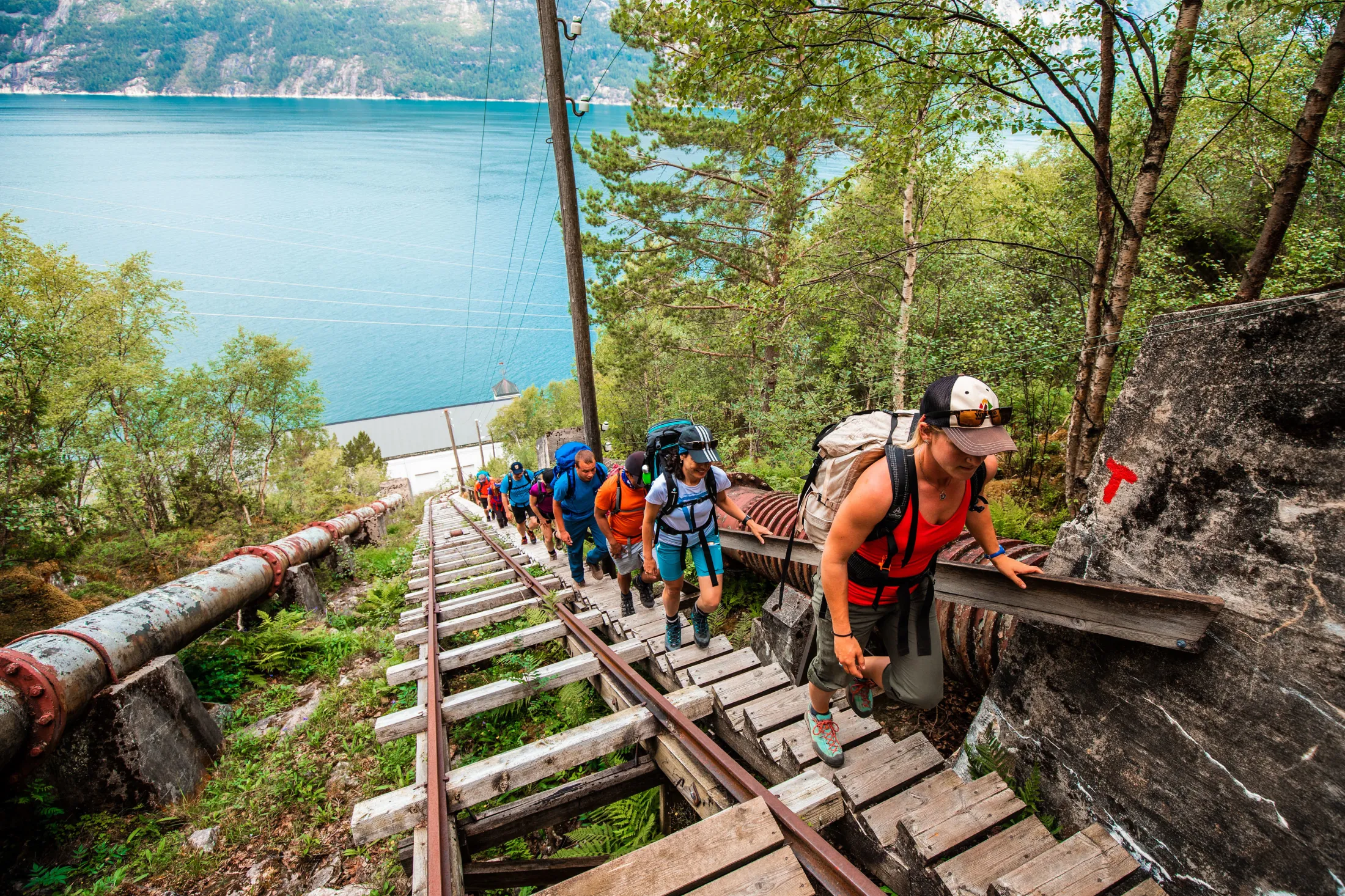 Several people hiking up a long staircase with a fjord in the background.
