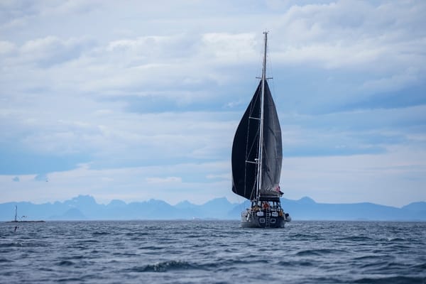 A sailing ship with black sails sailing on the open sea under a cloudy sky.