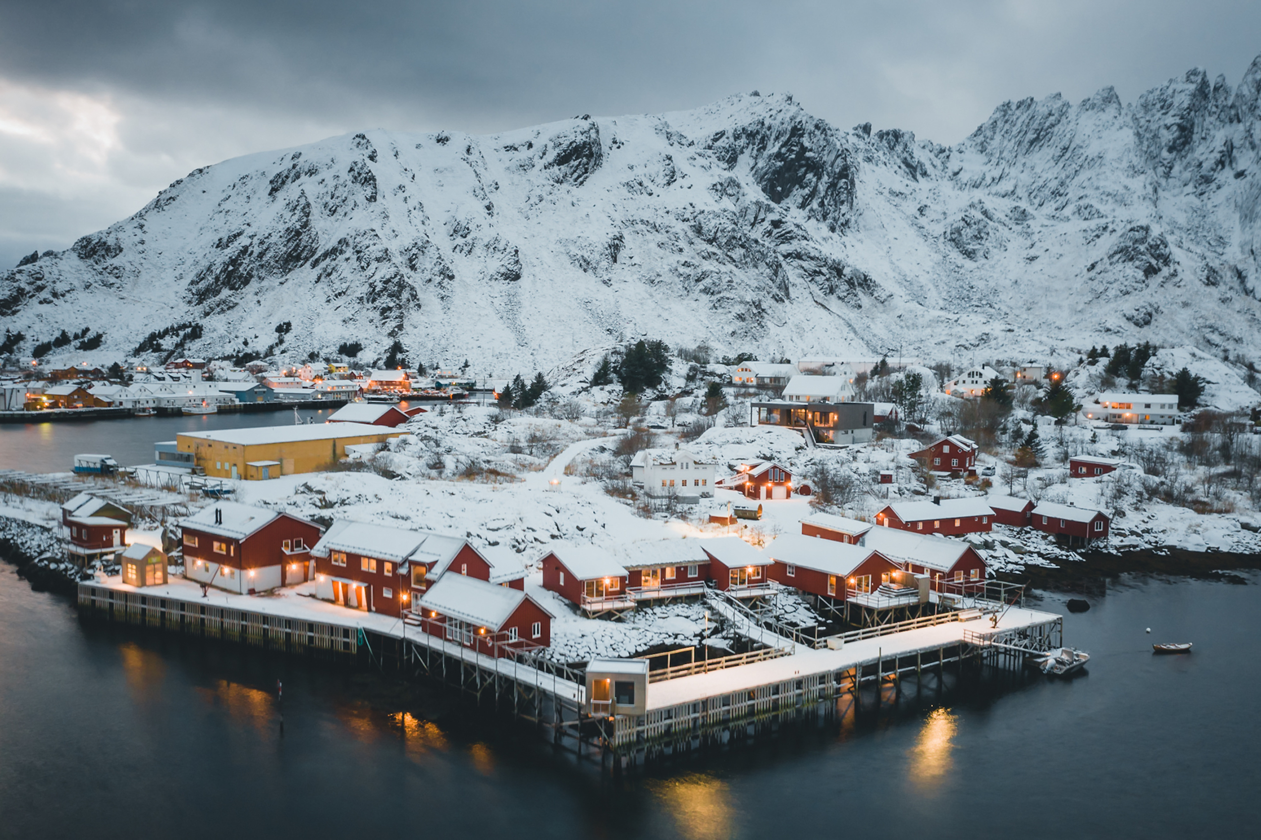 Snow covered village by the ocean with mountains behind