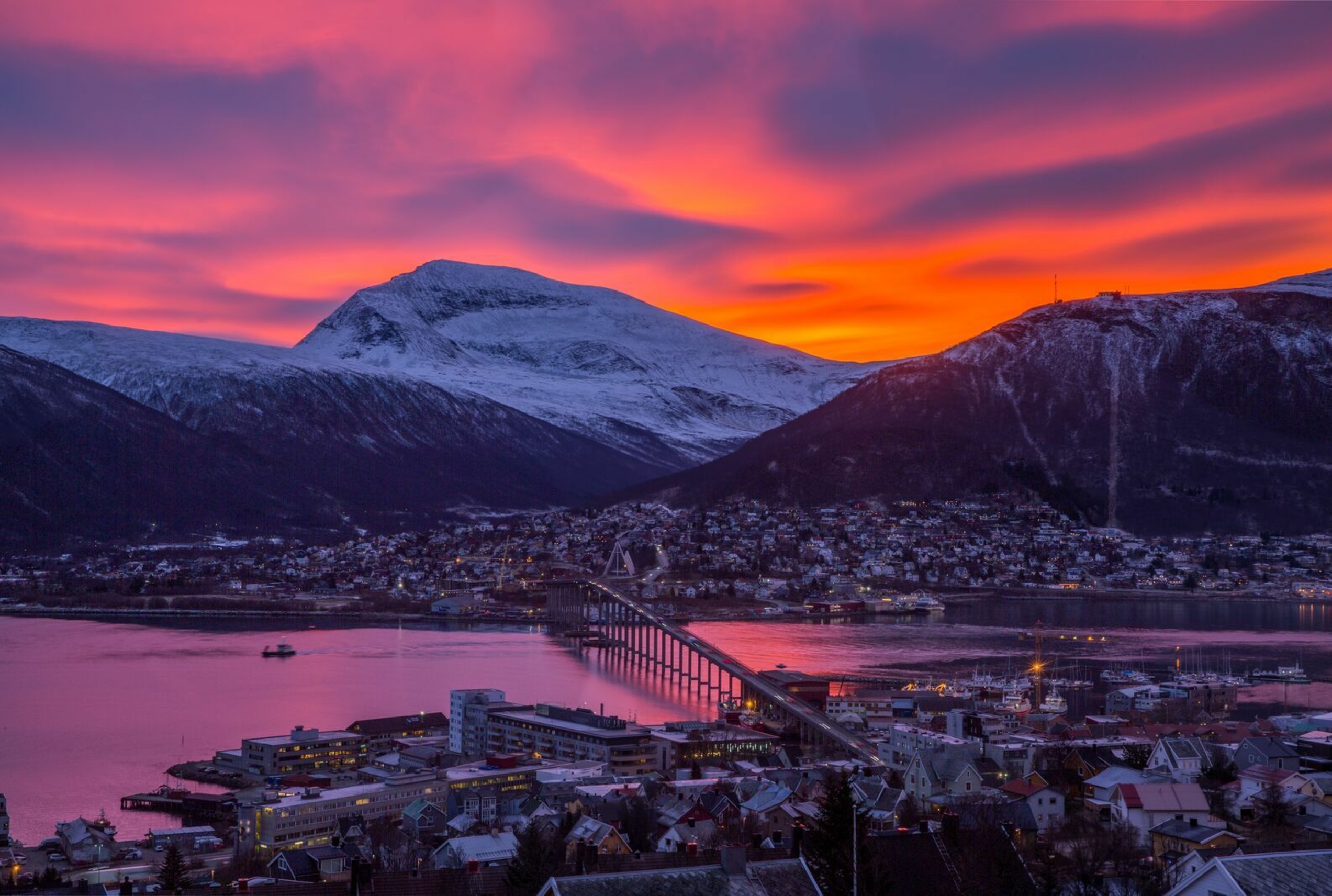 Pink and red sunset over a mountain and a city