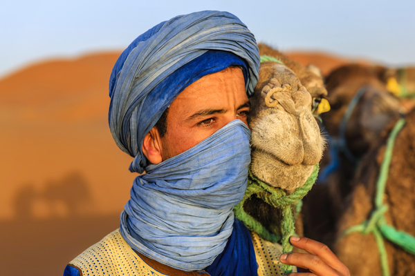 Man with scarf in the desert with camel