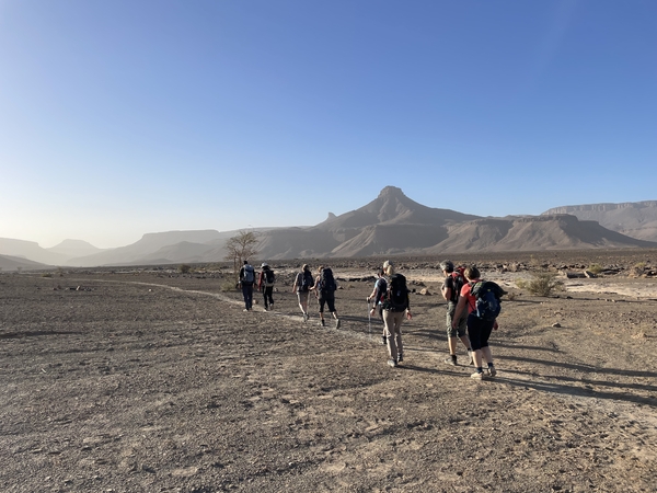 People trekking through the desert with mountains in the background