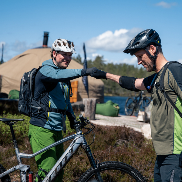 Two guys with bikes fist bumping