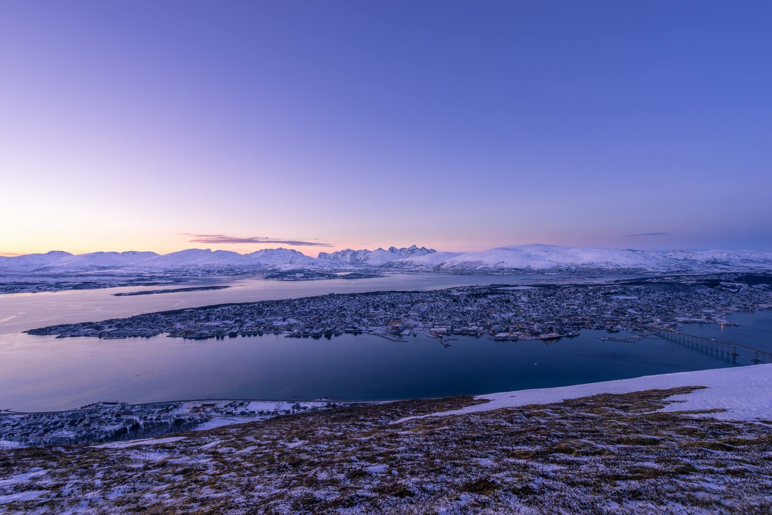 Purple sky over mountains and ocean with a city on an island