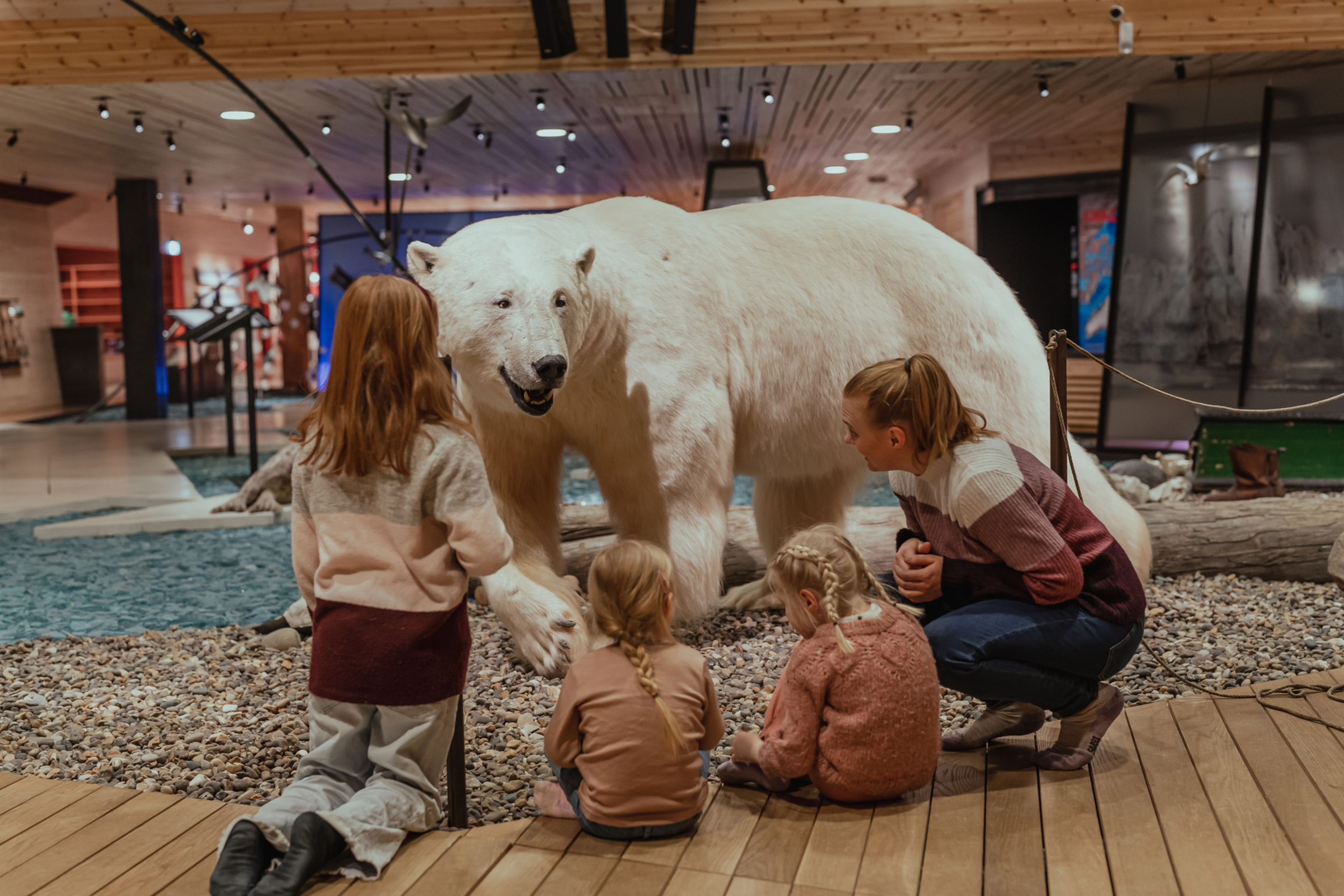 Stuffed polar bear with some kids observing it
