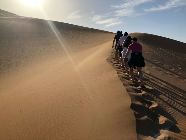 People hiking up a sand dune