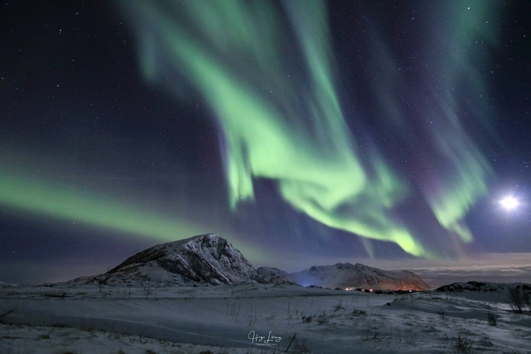 Northern lights over snowy mountains with stars