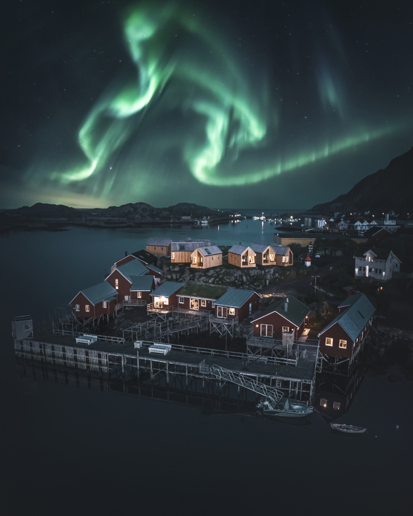 Northern lights over a small fishing village and mountains