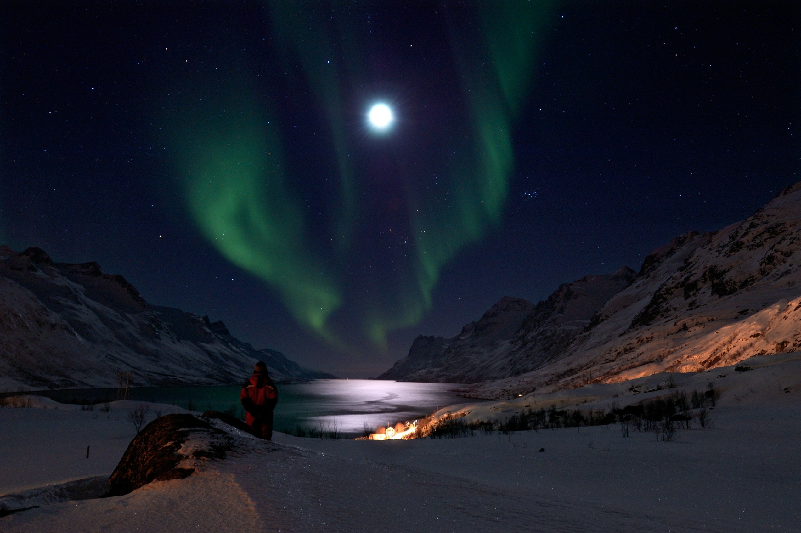 Northern Lights over a snowy fjord and mountains