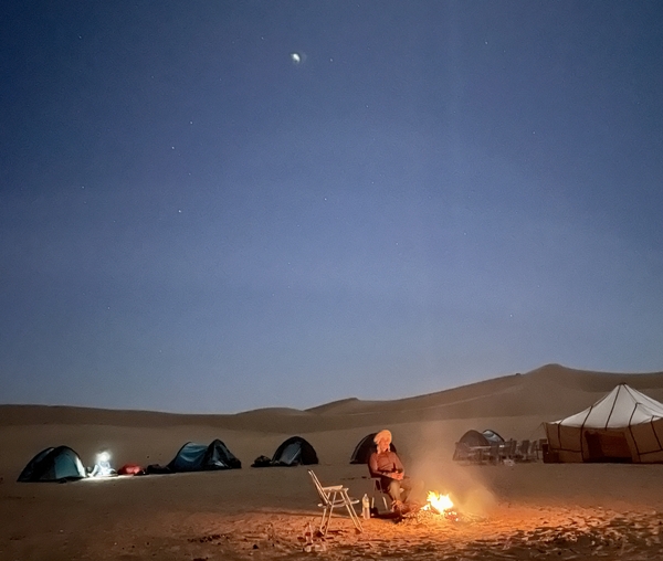 Man sitting in front of a bonfire in the camp site in the desert