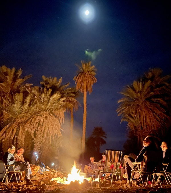 A group of people sitting infront a bonfire in the desert night