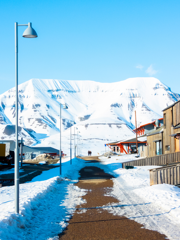 Midnight sun in a snowy landscape with a street going towards mountains