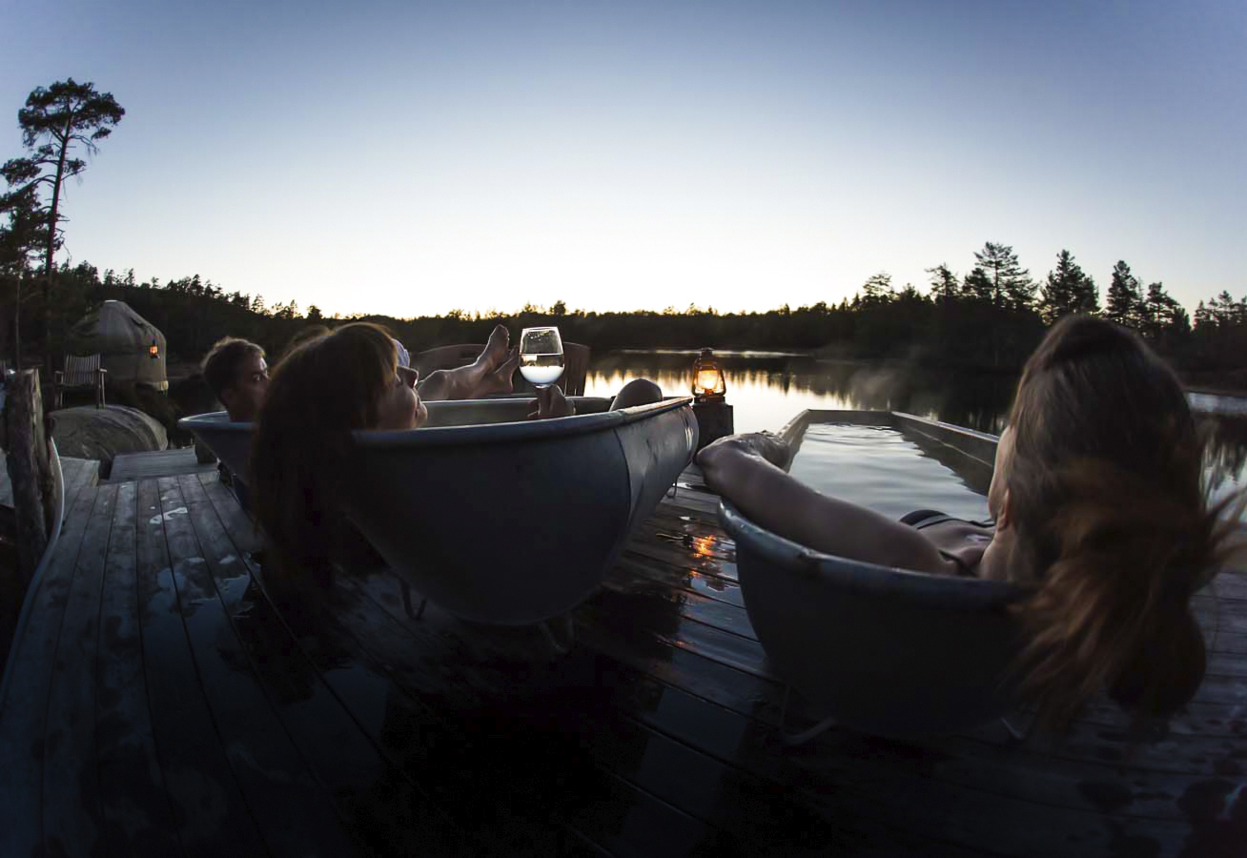 People laying in bat tubs outside in the forest
