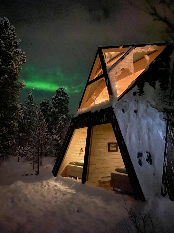 Cabin in the woods in snow with northern lights
