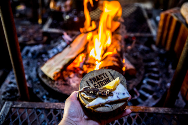 A hand holding cheese near a fire