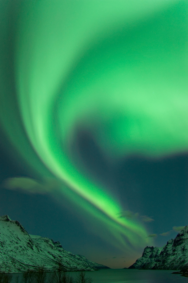 Northern lights over fjord and snow-capped mountains