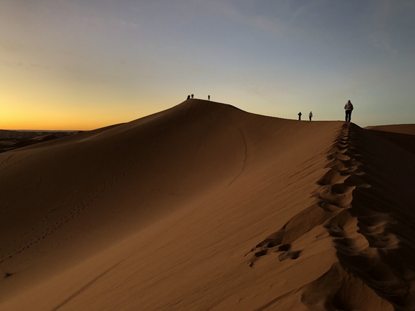 Walking on the ridge of sand dunes in the sunset