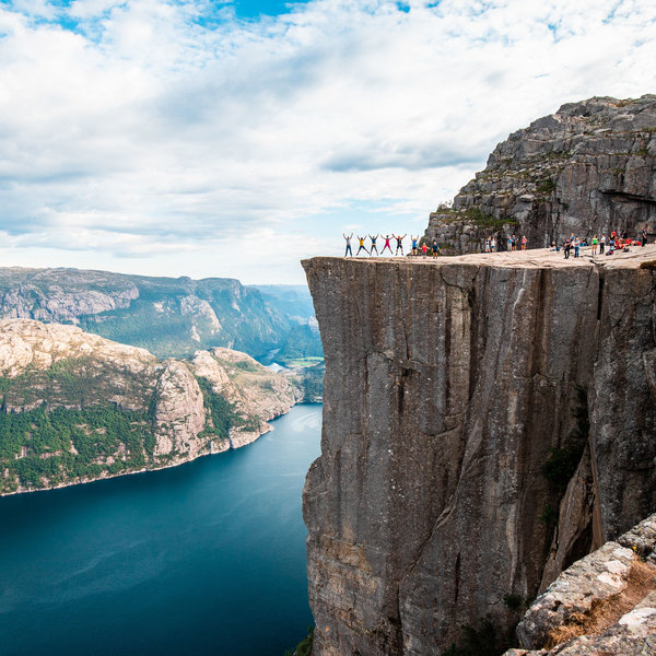 Fornøyde turgåere som nyter et hopp på Preikestolen med Lysefjorden i bakgrunnen
