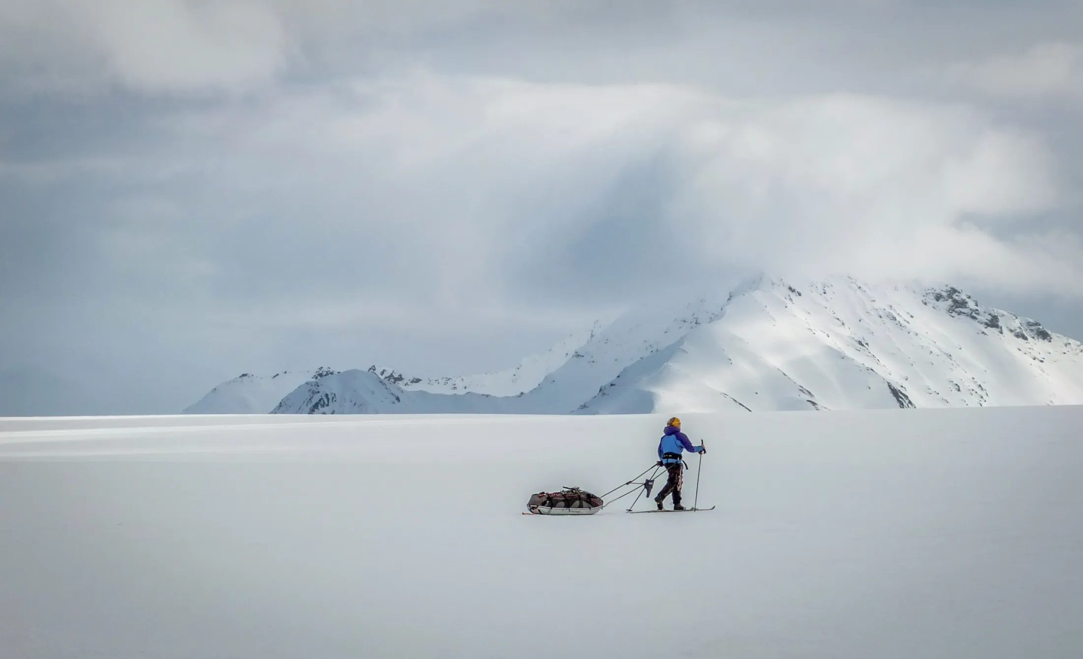 Person på fjellski med pulk i fjellet.