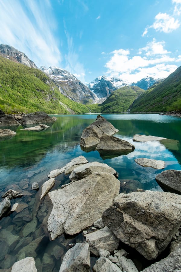 Steiner i et vann med fjell i bakgrunn.