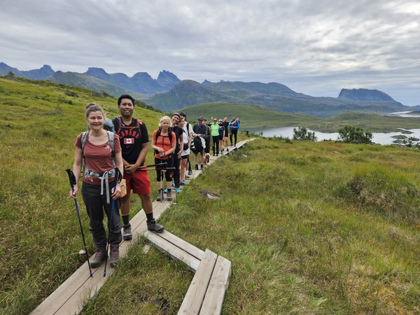 En gruppe turgåere på en kloppesti i et naturskjønn fjellandskap.