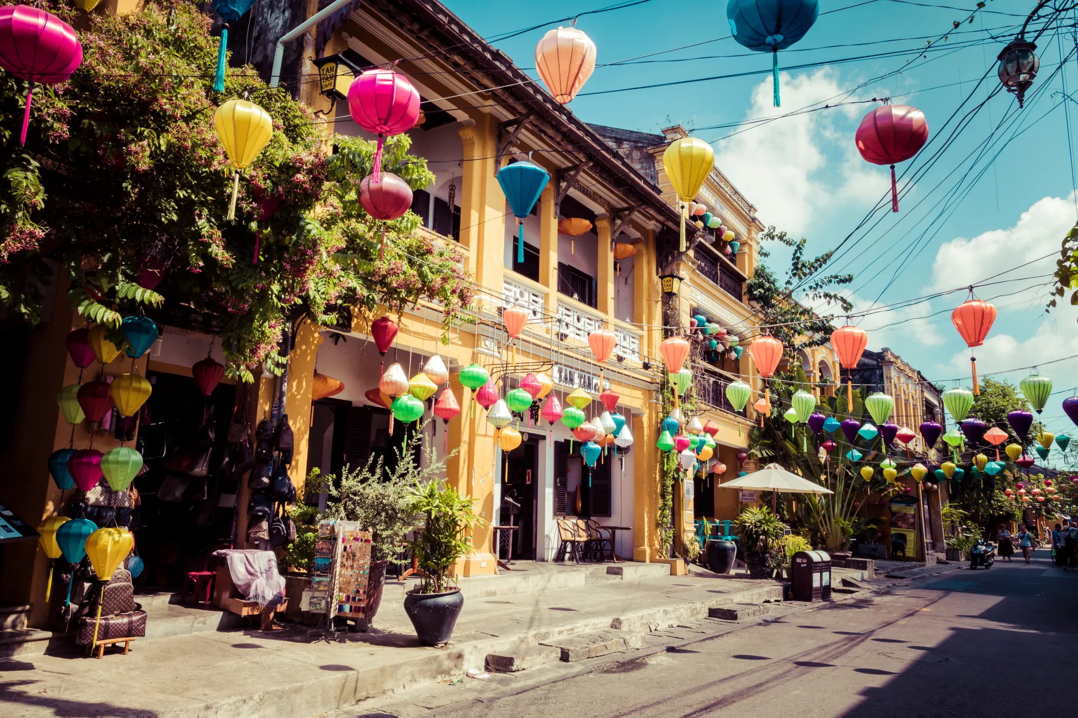 En livlig gammel gate i Hoi An i Vietnam, dekorert med fargerike papirlykter hengende over hodet.