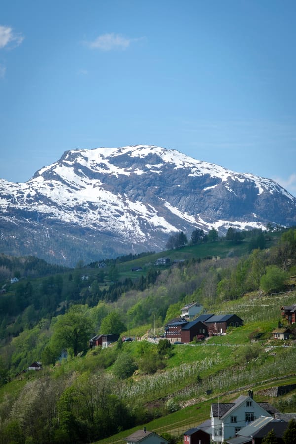 Gård med fjell i bakgrunn som har snø.