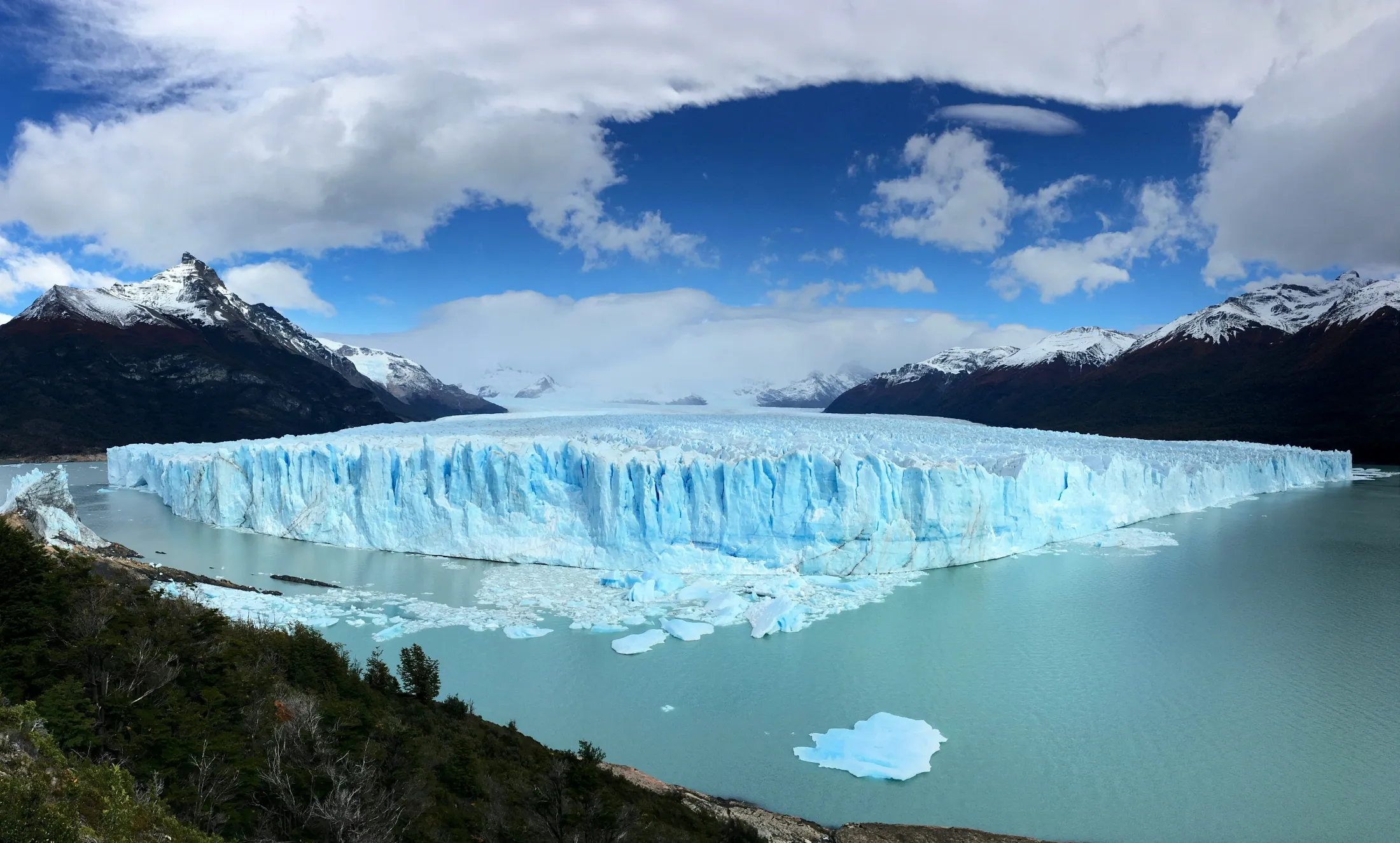 Perito Moreno-isbreen med grønnt brevann foran og fjell med snø på i bakgrunnen